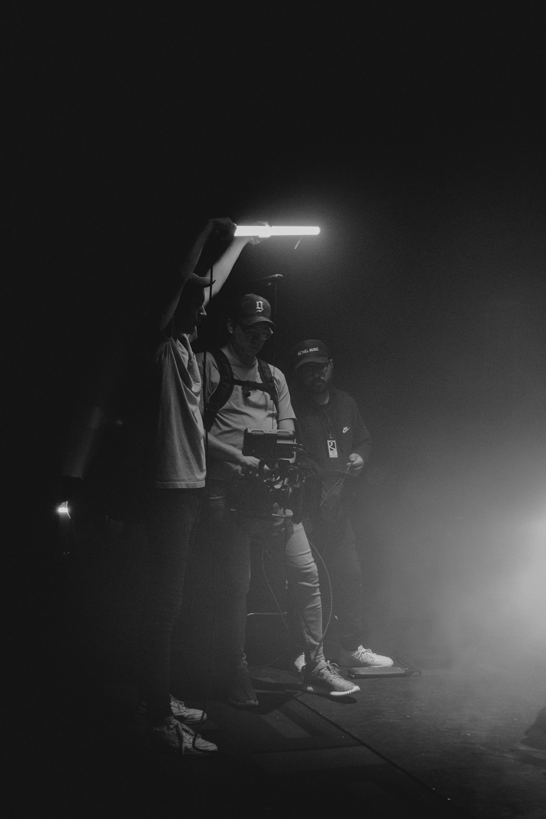 a-black-and-white-photo-of-three-people-in-the-dark-imyikwedewo