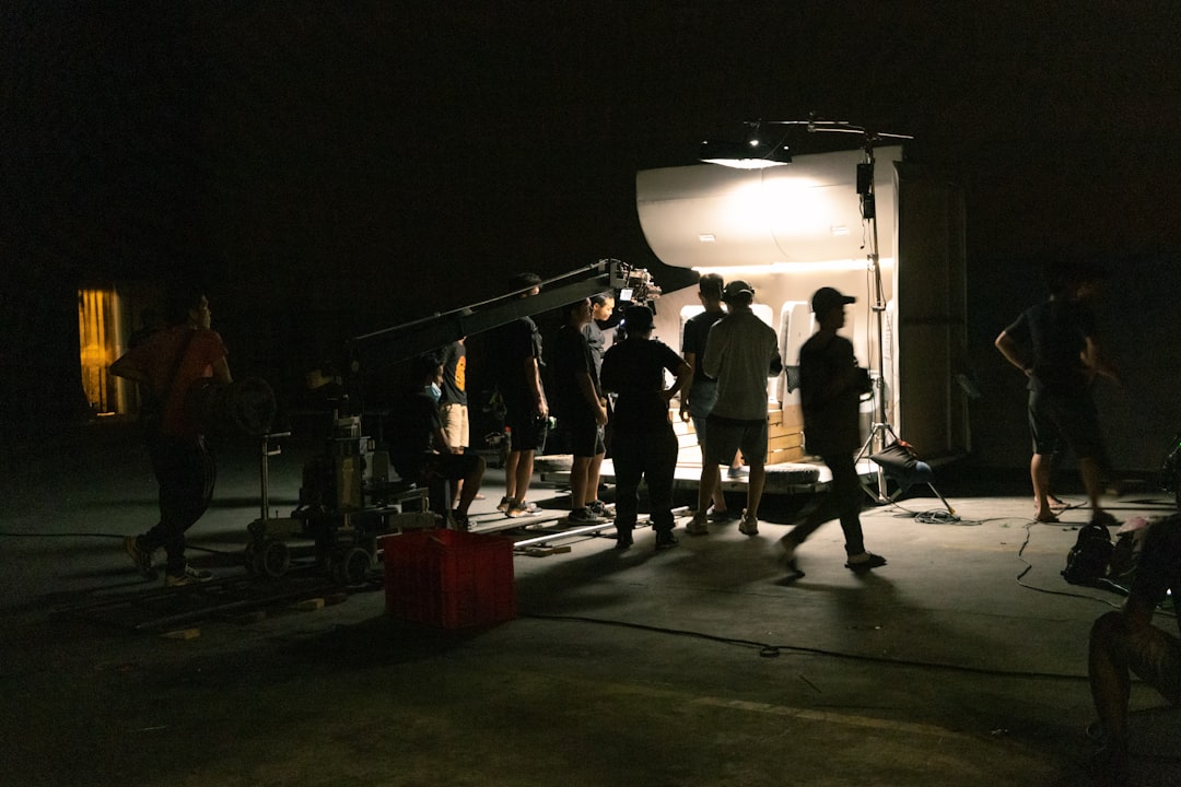 a-group-of-people-standing-around-a-camera-in-the-dark-lp24lfrfkis