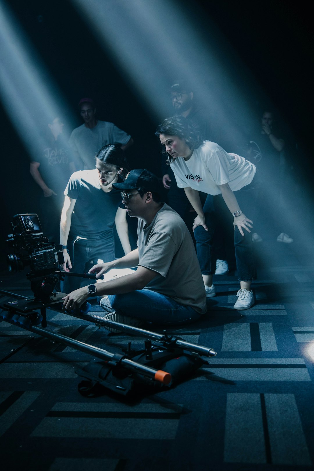 a-group-of-people-standing-around-a-camera-ony-jqsbvny