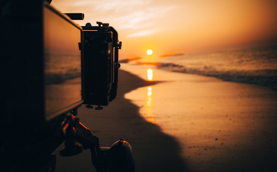 black-camera-on-tripod-by-the-beach-during-sunset-yl7irdzwch4